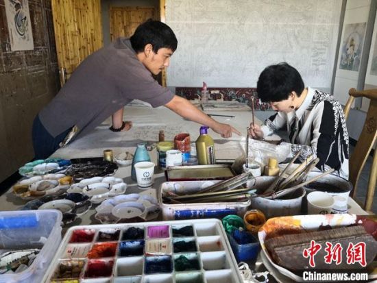 圖為2020年8月下旬，敦煌“80后”畫家張杰龍(左)在為云南麗江“學生”莫北講解敦煌壁畫的繪畫技巧?！●T志軍 攝
