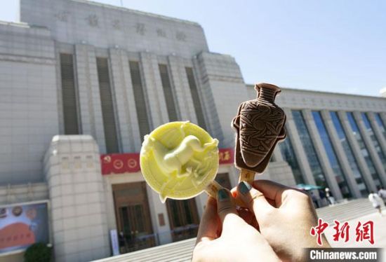 2021年7月30日，游客手拿“銅奔馬”“彩陶瓶”造型的雪糕，在甘肅省博物館前拍照打卡?！「哒?攝