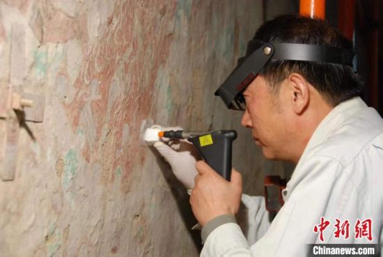 敦煌研究院研究員樊再軒進行壁畫修復。(資料圖)張云文 攝