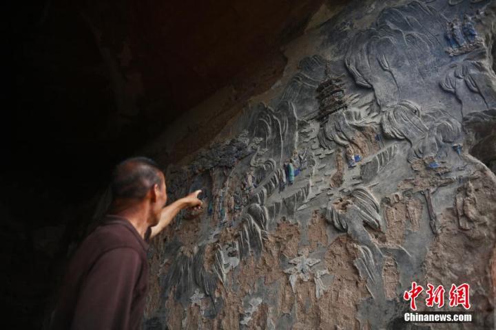 7月15日，甘肅省平?jīng)鍪袥艽h百里石窟長(zhǎng)廊羅漢洞石窟內(nèi)，該窟文保員郭建平介紹窟內(nèi)石刻彩繪壁畫(huà)。郭建平家中三代人曾自發(fā)保護(hù)羅漢洞石窟。羅漢洞石窟遺存40余個(gè)窟龕，以北魏至清代風(fēng)格為主。中新社記者 李亞龍 攝