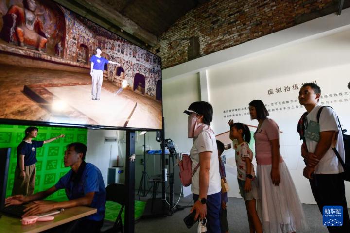 7月22日，游客體驗“尋境敦煌——數(shù)字敦煌沉浸展”后，在虛擬演播廳拍攝一段真人與洞窟虛擬場景交互的視頻。新華社記者 郎兵兵 攝</p>
<p>