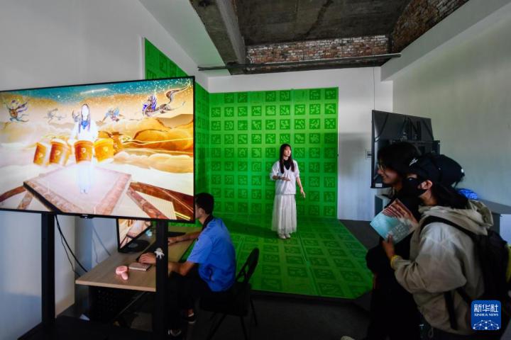 7月22日，游客體驗“尋境敦煌——數(shù)字敦煌沉浸展”后，在虛擬演播廳拍攝一段真人與洞窟虛擬場景交互的視頻。新華社記者 郎兵兵 攝</p>
<p>